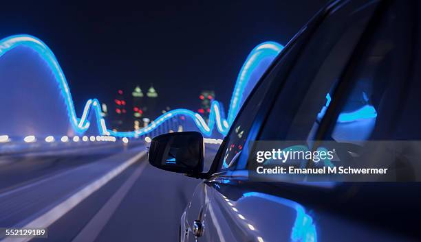 car driving nights over illuminated bridge - united arab emirates night stock pictures, royalty-free photos & images