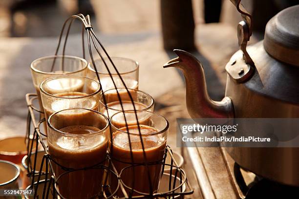 glasses of chai kept in grid tray with kettle on stove - chai tea stock pictures, royalty-free photos & images