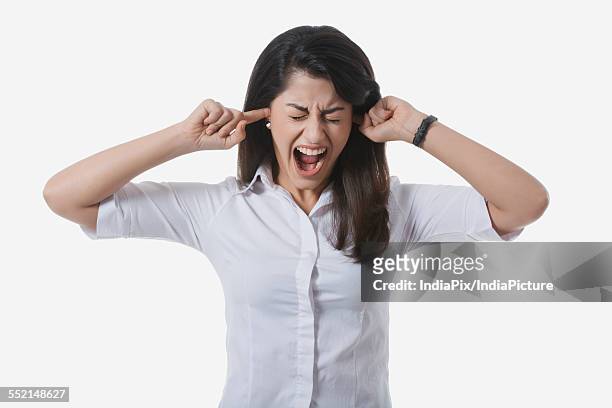 frustrated businesswoman with fingers in ears yelling against white background - woman fingers in ears stock pictures, royalty-free photos & images