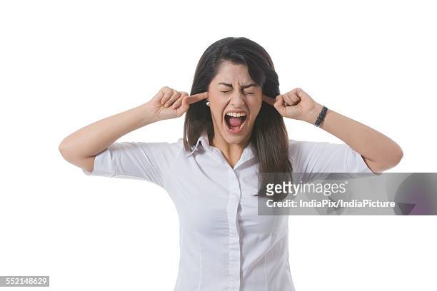 frustrated businesswoman with fingers in ears shouting over white background - woman fingers in ears stock pictures, royalty-free photos & images