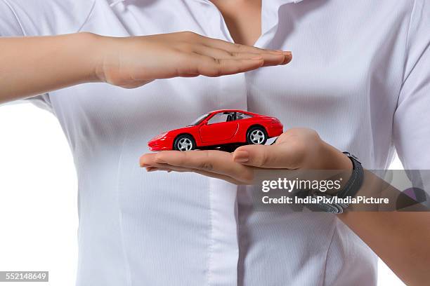 midsection of insurance agent covering toy car against white background - car insurance agent stock pictures, royalty-free photos & images