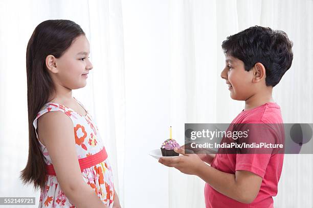 boy giving cupcake to a girl - cupcakes girls fotografías e imágenes de stock