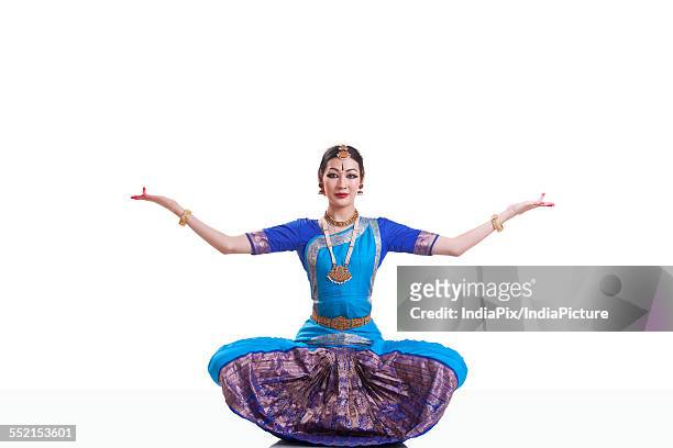 portrait of dancer with arms outstretched performing bharatanatyam against white background - bharatanatyam indischer tanzstil stock-fotos und bilder