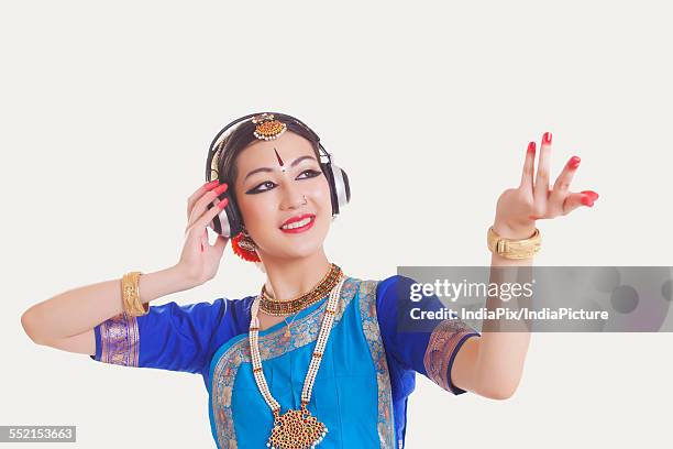 bharatanatyam dancer wearing headphones while dancing over white background - bharatanatyam dancing stockfoto's en -beelden