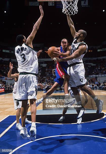 Guard Jon Barry of the Detroit Pistons drives between center Loren Woods and forward Gary Trent of the Minnesota Timberwolves during the NBA game at...