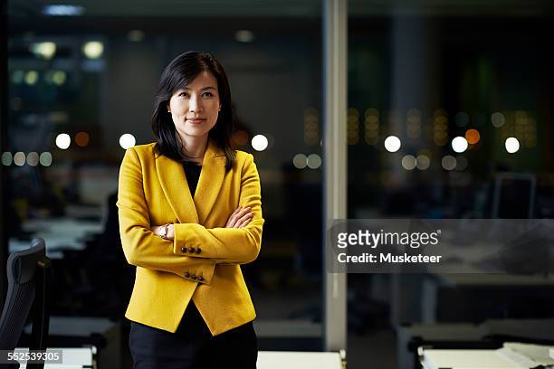woman standing in office at night - three quarter length stock pictures, royalty-free photos & images