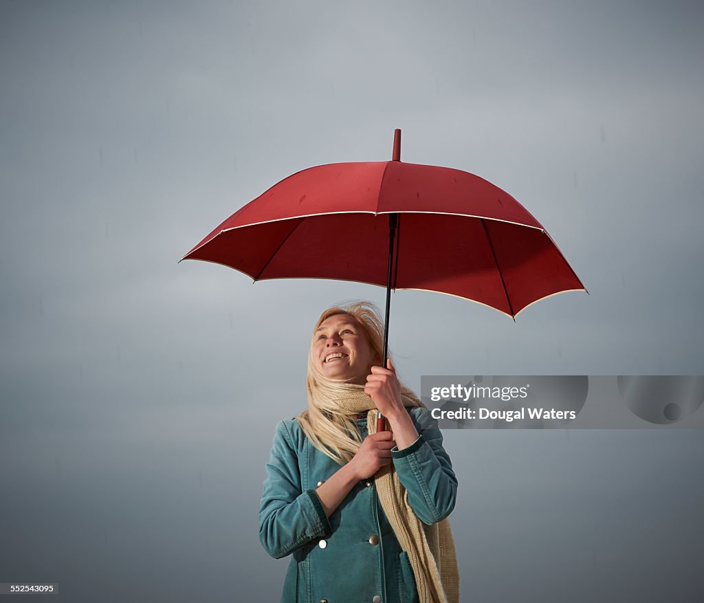 Woman holding red umbrella in the rain.