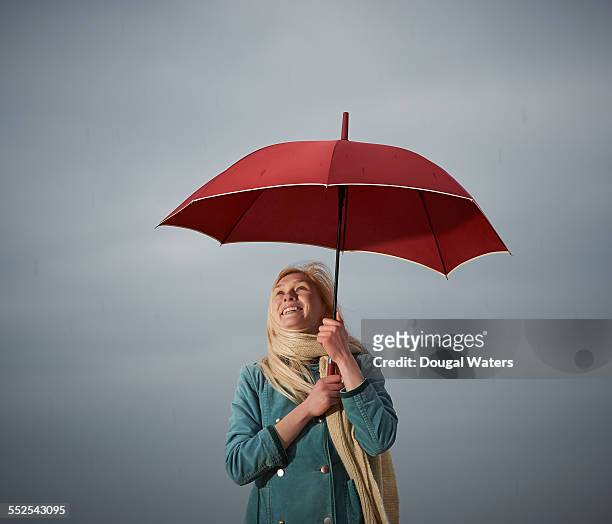 woman holding red umbrella in the rain. - holding umbrella stock pictures, royalty-free photos & images