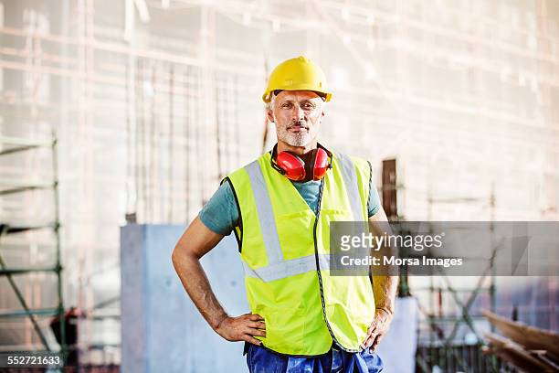confident architect standing at construction site - protective workwear photos et images de collection