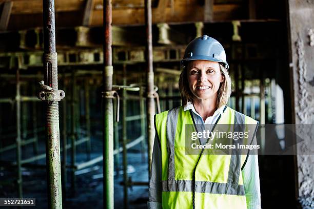 happy female architect at construction site - reflecterende kleren stockfoto's en -beelden