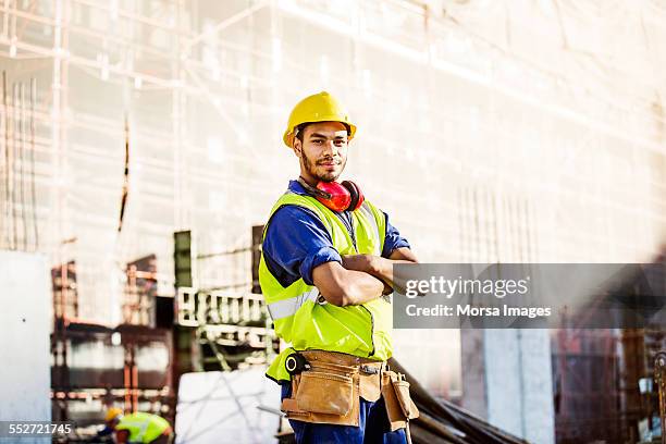 confident construction worker standing at site - confident young man at work stock pictures, royalty-free photos & images