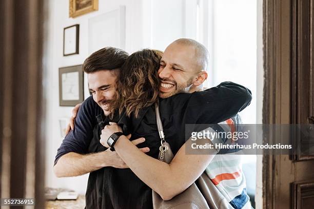 gay couple welcoming their mother at the door - drei erwachsene stock-fotos und bilder