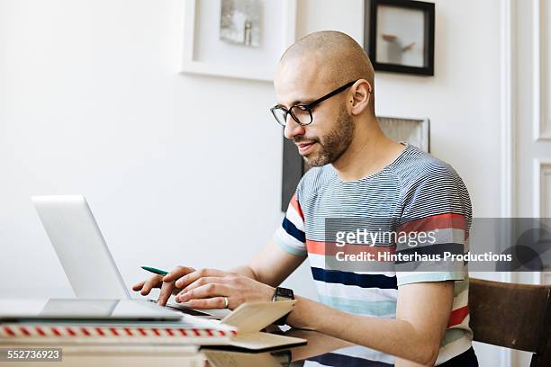 bald man working on laptop at home - mid adult men stock pictures, royalty-free photos & images