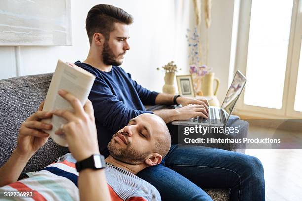 gay couple enjoying togetherness on sofa - book sleeve stock pictures, royalty-free photos & images