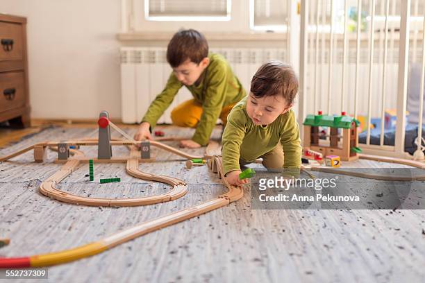 young boy and baby boy playing indoors - miniature train stock pictures, royalty-free photos & images