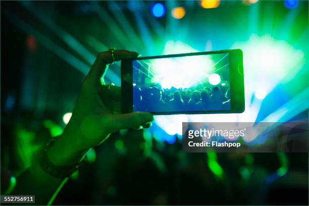 woman taking a photo with phone at music event - bash 2015 concert stock-fotos und bilder