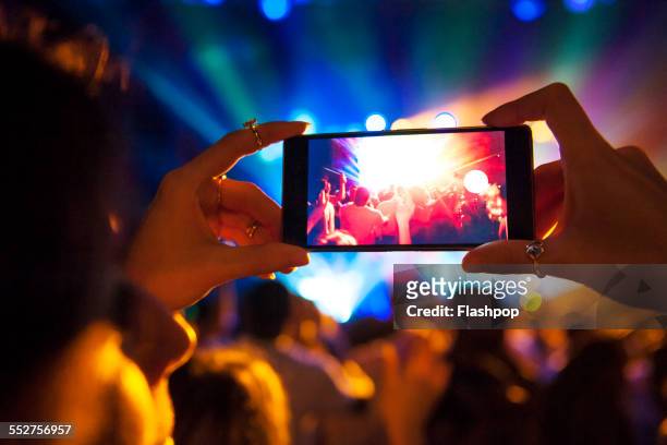 woman taking a photo with phone at music event - networks shining a light concert foto e immagini stock