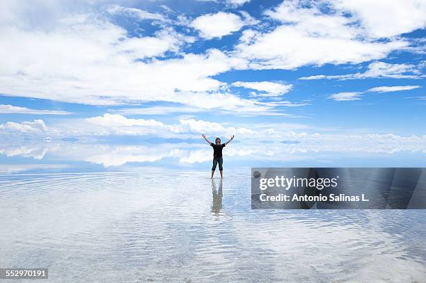 a young adult posing on the uyuni salar. bolivia - cloud sales fotografías e imágenes de stock