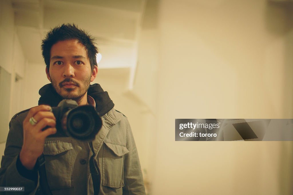 Japanese man taking a photo of himself in mirror