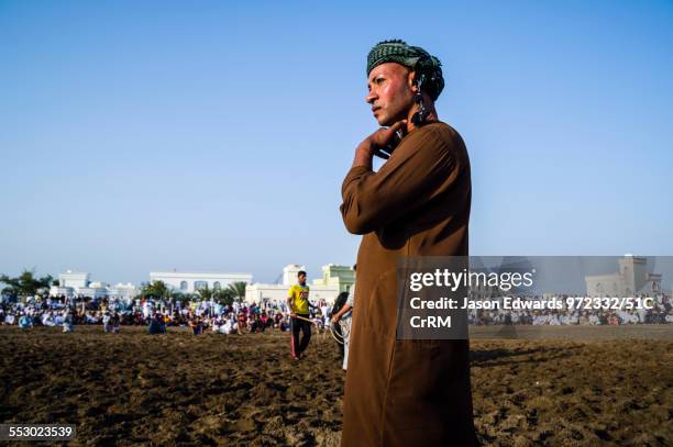 An official uses a wooden cane to ensure the Brahman bulls do not become entangled in their ropes. Al Sharadi, Seeb, Muscat, Sultanate of Oman.