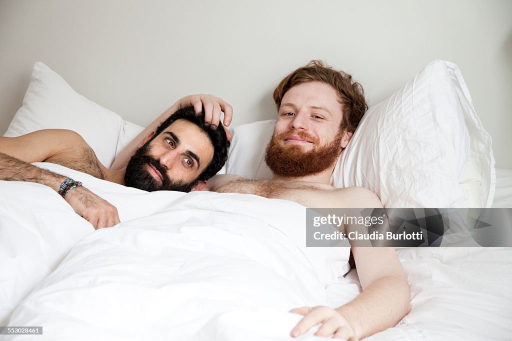 Gay couple cuddling in bed