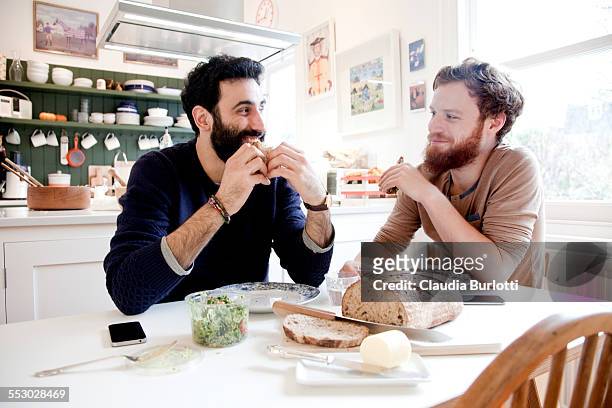 gay couple eating lunch at home - mid adult men stock pictures, royalty-free photos & images