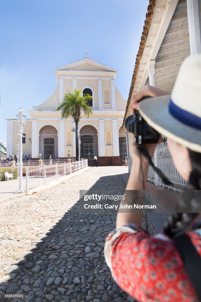 Woman takes photo of church in Trinidad, Cuba