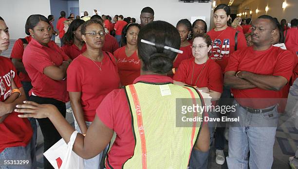 Volunteers receive directions in the Reliant Center on how to prepare forms that some evacuees must complete to receive a $2,000 debit card from the...