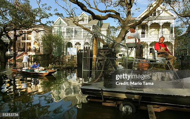 Rescue workers look on as civilians paddle a boat down a flooded street in the Garden District September 7, 2005 in New Orleans, Louisiana....