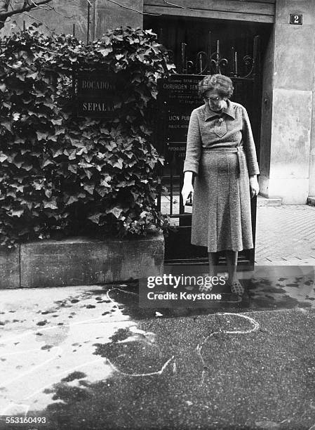 Madame Favier, the caretaker of the apartment building at 2 Rue des Dardanelles in Paris, points to the chalk outline marking the position of the...
