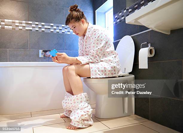 teenager social networking in bathroom - girl sitting stock-fotos und bilder
