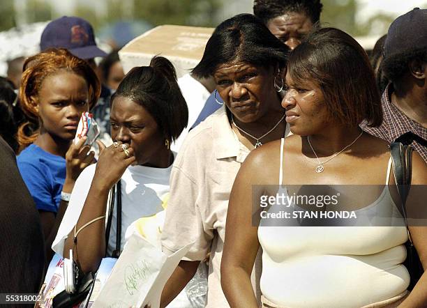 Houston, UNITED STATES: Women wait with a crowd of Hurricane Katrina evacuees in the hot sun as they line up to receive a debit card from the Red...