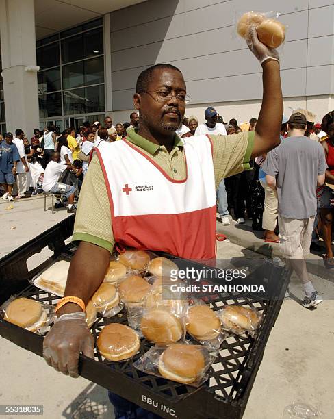 Houston, UNITED STATES: Michael Malone of the Red Cross distributes sandwiches to Hurricane Katrina evacuees as they line up to receive a debit card...