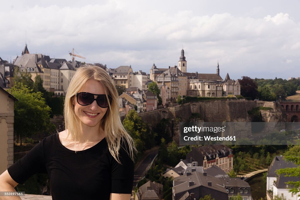 Luxembourg, Luxembourg City, portrait of smiling woman in front of city view