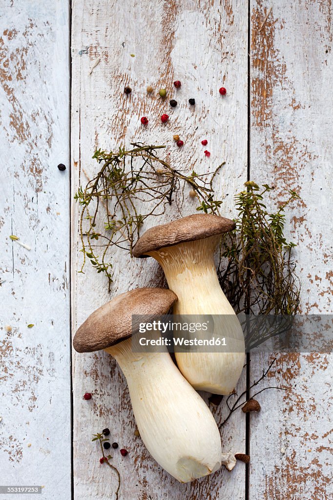 King trumpet mushrooms, thyme and peppercorns on wood
