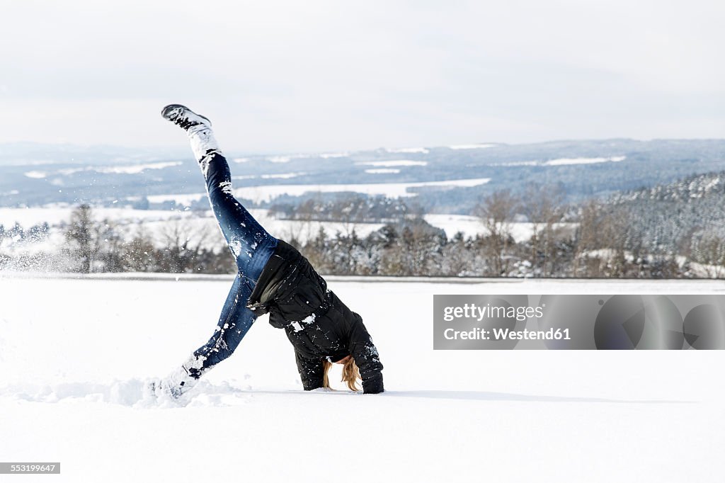 Germany, Baden-Wuerttemberg, Waldshut-Tiengen, playful woman in snow doing a cartwheel