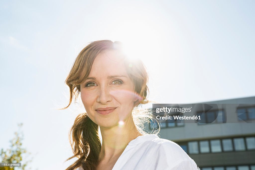 Portrait of smiling businesswoman at backlight