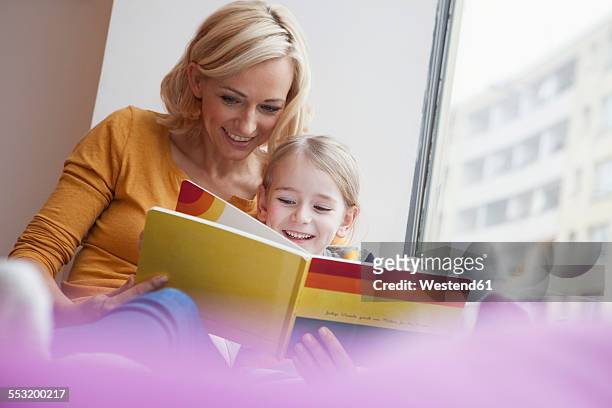 mother reading picture book to daughter - love books stock-fotos und bilder