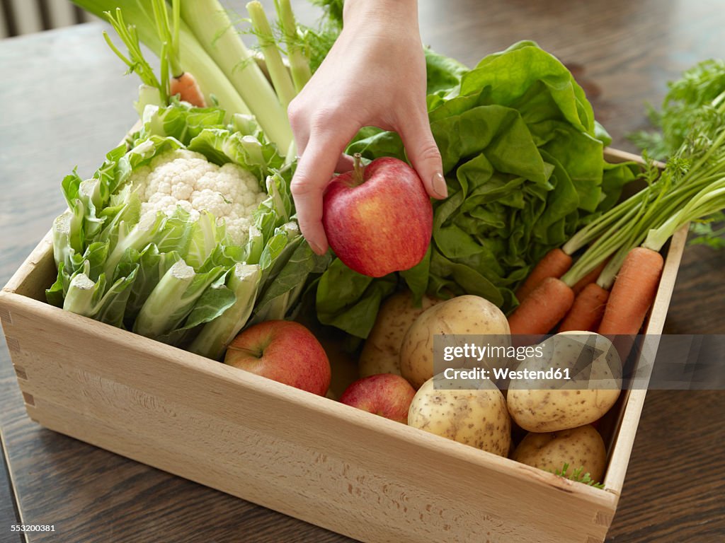 Hand taking crate with fresh fruit and vegetables