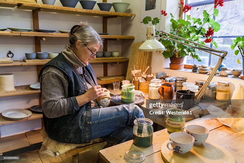 Potter in workshop painting a bowl