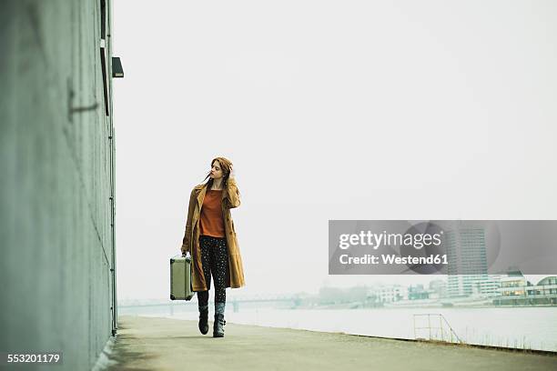 young woman with suitcase walking by the riverside - 18 19 anni foto e immagini stock