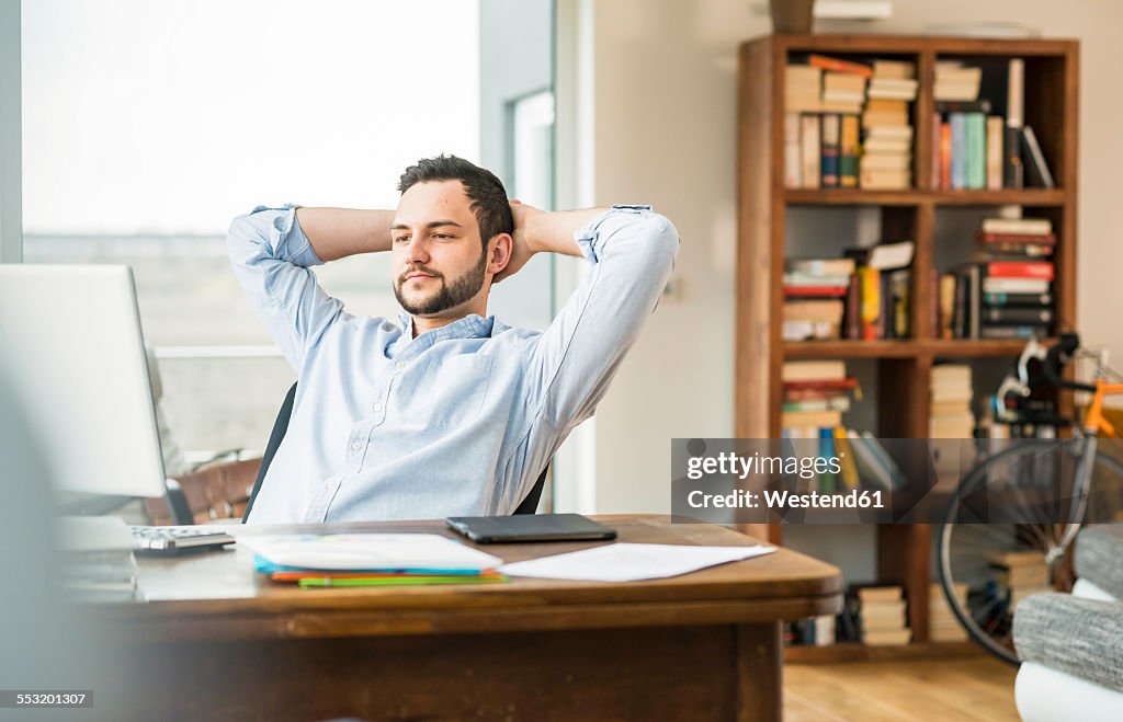 Young man at desk leaning back