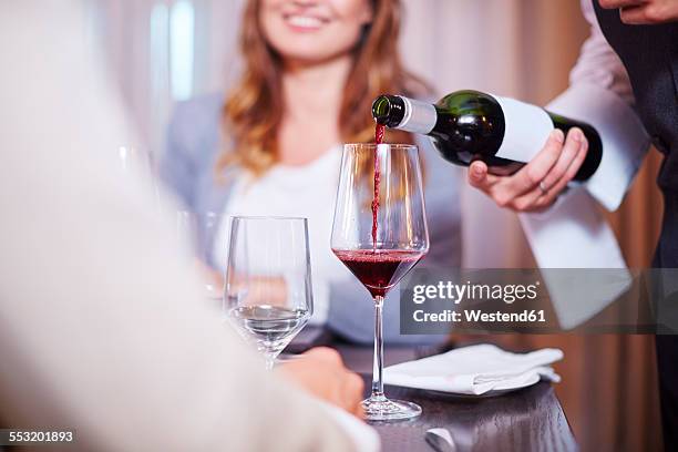 waiter pouring wine for business associates at hotel restaurant - meal expense stock pictures, royalty-free photos & images