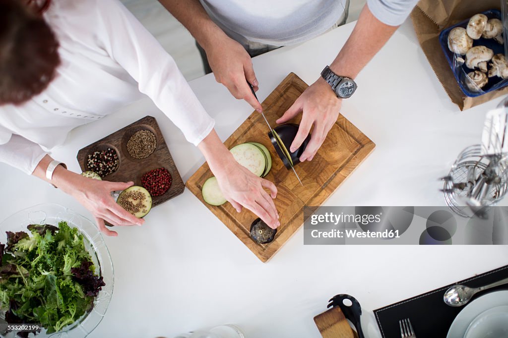 Couple in kitchen preparing eggplant