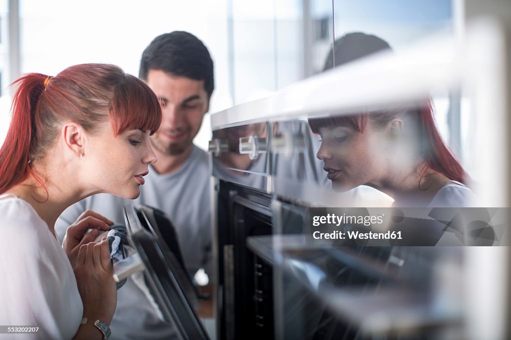 Couple in kitchen looking in oven