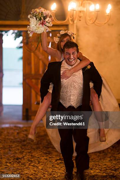 happy groom carrying bride piggyback in lobby - naughty bride stock pictures, royalty-free photos & images