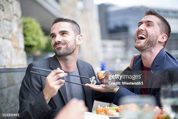 gay couple eating sushi at outdoor restaurant - japanese food stock pictures, royalty-free photos & images