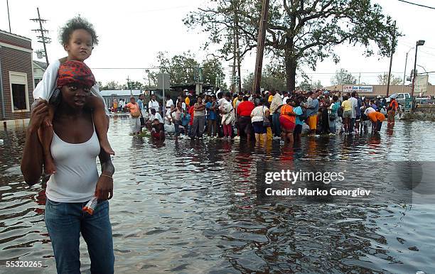 Lynell Wright carries Luric Johnson through a flooded intersection crowded with survivors awaiting rescue at the St. Cloud bridge on August 30 a day...