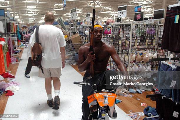 Looter caries a rifle while riding a bike in a K-Mart in the Garden District in New Orleans, Louisiana on August 30, 2005 after Hurricane Katrina...