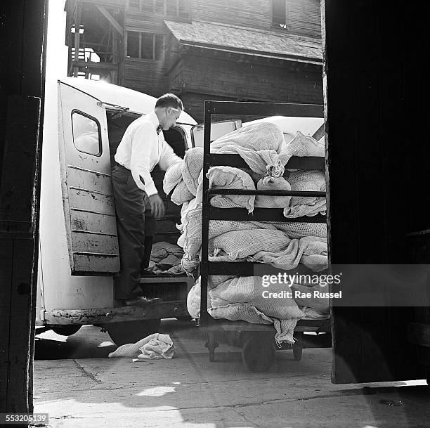 Delivery man for Crib Diaper Service unloads the day's deliveries of cloth diapers, Brooklyn, New York, New York, 1947.